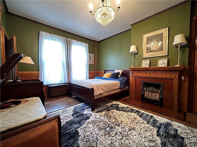 110 Edgar James St, Kane Boro, PA 16735 - bedroom featuring crown molding, a wainscoted wall, a chandelier, wood finished floors, and a brick fireplace
