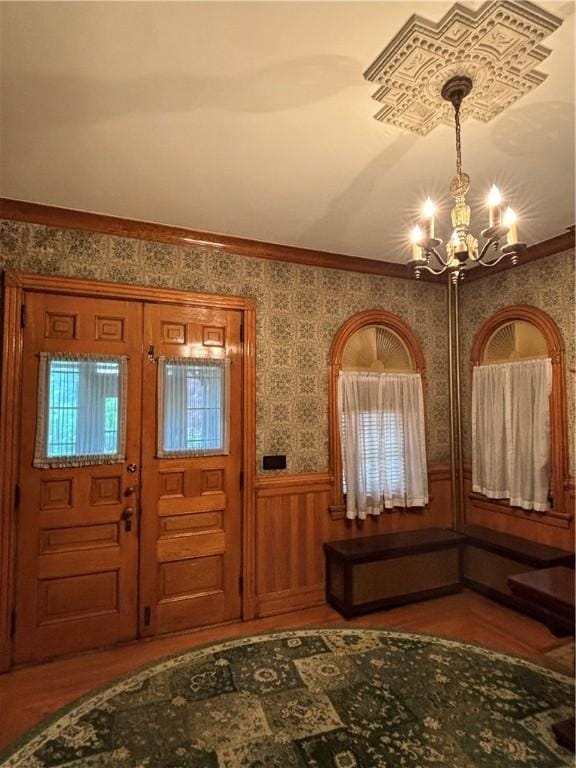 110 Edgar James St, Kane Boro, PA 16735 - entrance foyer with a chandelier, wallpapered walls, a wainscoted wall, wood finished floors, and crown molding