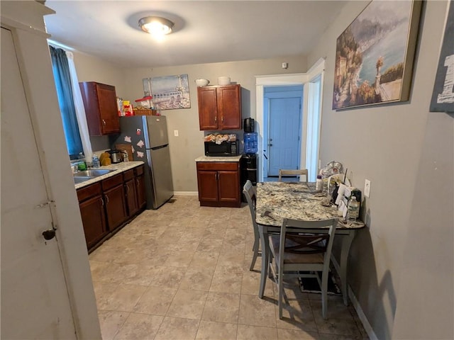 313 Ellicott St, Rochester, NY 14619 - kitchen with black microwave, light countertops, freestanding refrigerator, and a sink