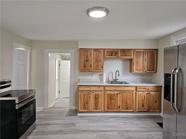 11 Bryant St, Utica, NY 13502 - kitchen with appliances with stainless steel finishes, a sink, light countertops, brown cabinetry, and light wood-style flooring