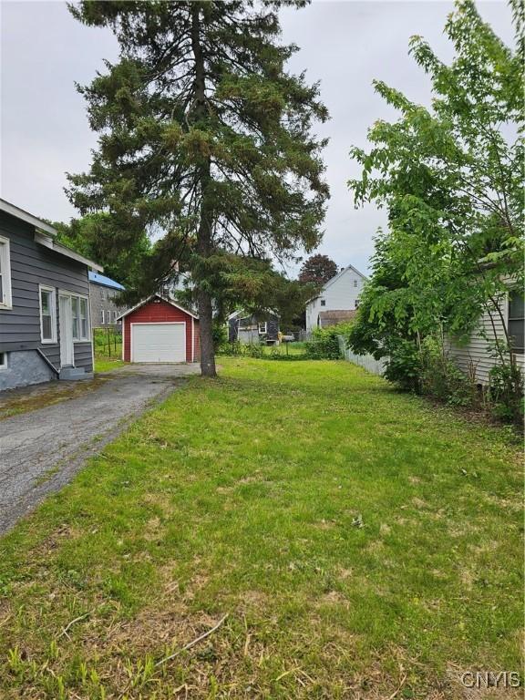 11 Bryant St, Utica, NY 13502 - view of grassy yard with a garage, an outdoor structure, and asphalt driveway