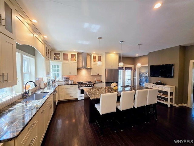 34 Maple St, Ellery, NY 14712 - kitchen with stainless steel appliances, wall chimney exhaust hood, a sink, dark wood-style flooring, and a breakfast bar area