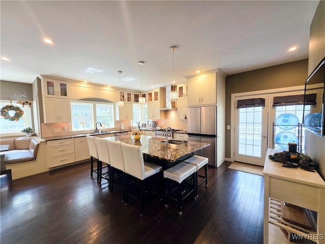 34 Maple St, Ellery, NY 14712 - kitchen with freestanding refrigerator, wall chimney exhaust hood, a kitchen island with sink, glass insert cabinets, and recessed lighting