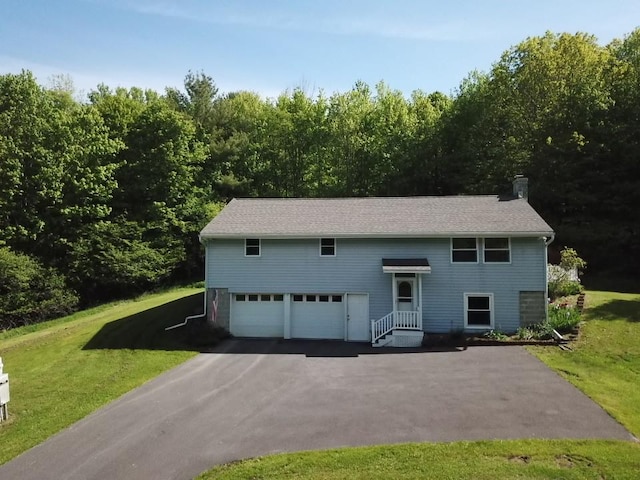 606 County Highway 12, Laurens, NY 13796 - view of front of house with an attached garage, driveway, a front yard, a chimney, and a forest view
