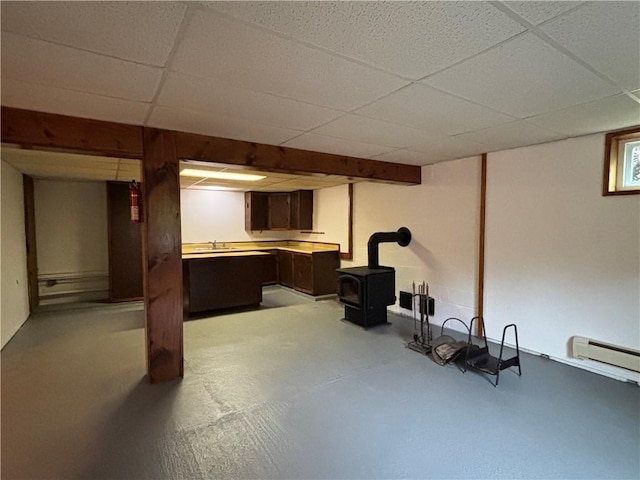606 County Highway 12, Laurens, NY 13796 - finished below grade area featuring a wood stove, a drop ceiling, baseboard heating, and a sink