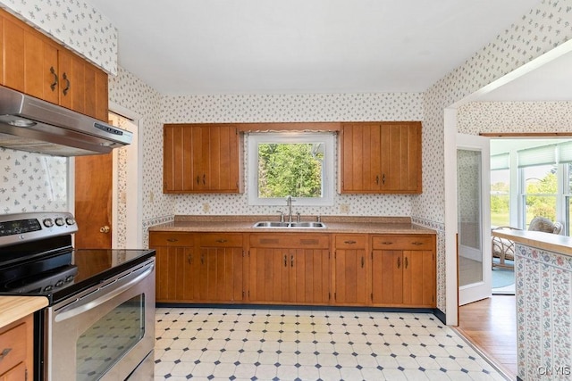 299 Sharp Rd, Granby, NY 13069 - kitchen featuring stainless steel electric range, wallpapered walls, a sink, under cabinet range hood, and brown cabinets