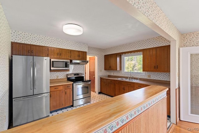 299 Sharp Rd, Granby, NY 13069 - kitchen with appliances with stainless steel finishes, wallpapered walls, a sink, under cabinet range hood, and light countertops