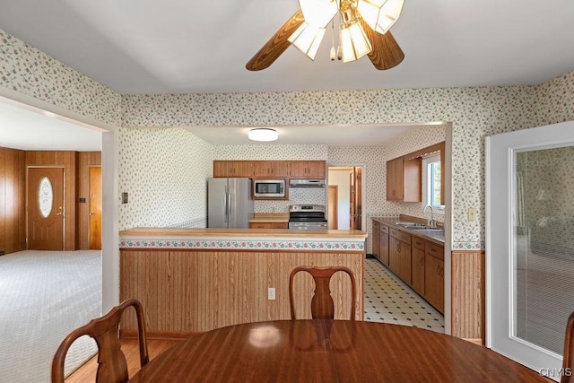 299 Sharp Rd, Granby, NY 13069 - kitchen with stainless steel appliances, wallpapered walls, a sink, a peninsula, and under cabinet range hood