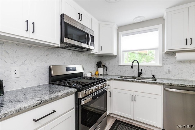 195 Robert Dr, North Tonawanda, NY 14120 - kitchen featuring appliances with stainless steel finishes, a sink, white cabinetry, light stone countertops, and backsplash