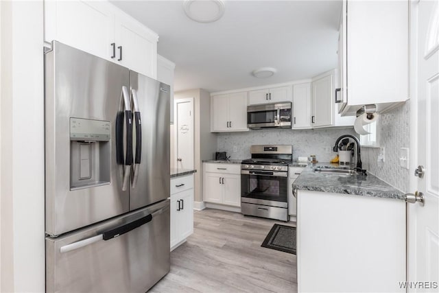 195 Robert Dr, North Tonawanda, NY 14120 - kitchen with stainless steel appliances, a sink, white cabinets, light wood-style floors, and dark stone counters