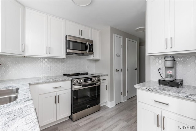 195 Robert Dr, North Tonawanda, NY 14120 - kitchen featuring appliances with stainless steel finishes, white cabinetry, light wood-style floors, backsplash, and light stone counters
