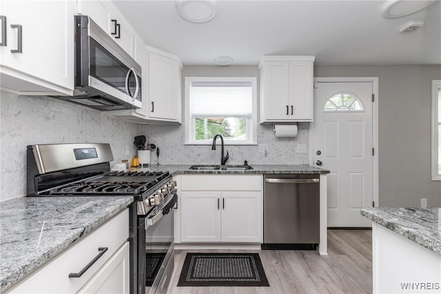 195 Robert Dr, North Tonawanda, NY 14120 - kitchen featuring appliances with stainless steel finishes, a sink, light wood-type flooring, backsplash, and white cabinets