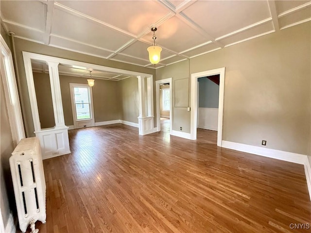 140 Maple St, Le Ray, NY 13612 - empty room featuring ornate columns, coffered ceiling, radiator, wood finished floors, and baseboards