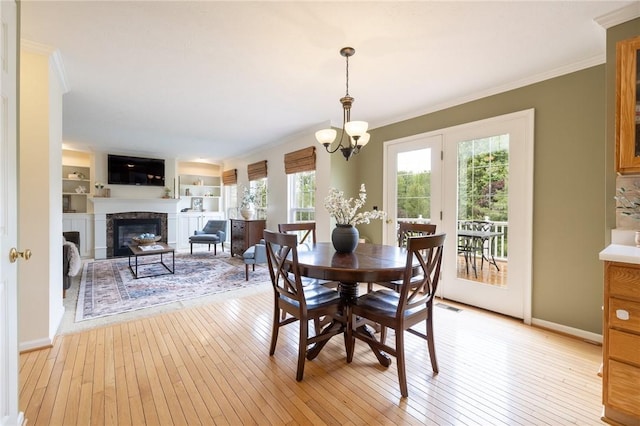 717 Westwood Trl, Walworth, NY 14502 - dining space featuring a chandelier, ornamental molding, light wood-style flooring, a glass covered fireplace, and baseboards