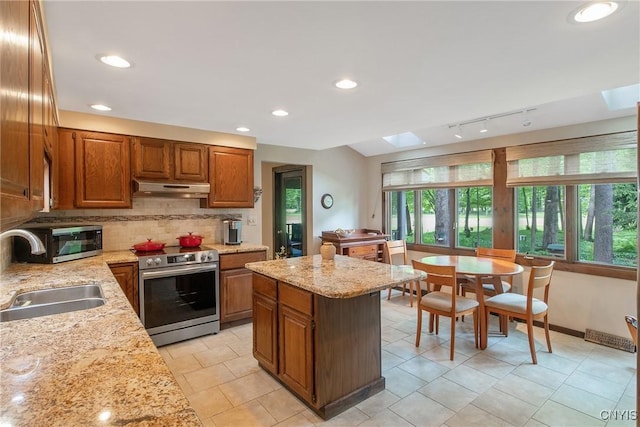 8807 Wandering Way, Lysander, NY 13027 - kitchen featuring stainless steel appliances, a sink, under cabinet range hood, tasteful backsplash, and brown cabinets
