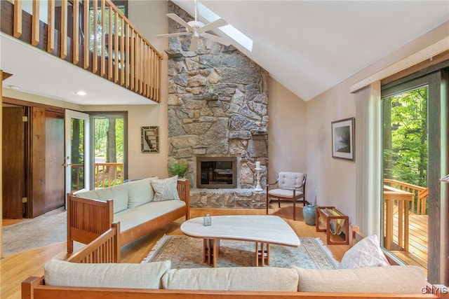 8807 Wandering Way, Lysander, NY 13027 - living area featuring a ceiling fan, high vaulted ceiling, wood finished floors, a stone fireplace, and a skylight