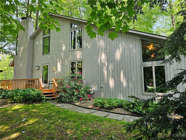 8807 Wandering Way, Lysander, NY 13027 - back of house featuring a chimney, a wooden deck, and board and batten siding