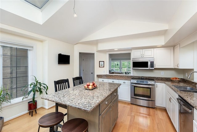 716 Mariner Cir, Webster, NY 14580 - kitchen featuring stainless steel appliances, a sink, a breakfast bar area, lofted ceiling, and white cabinetry