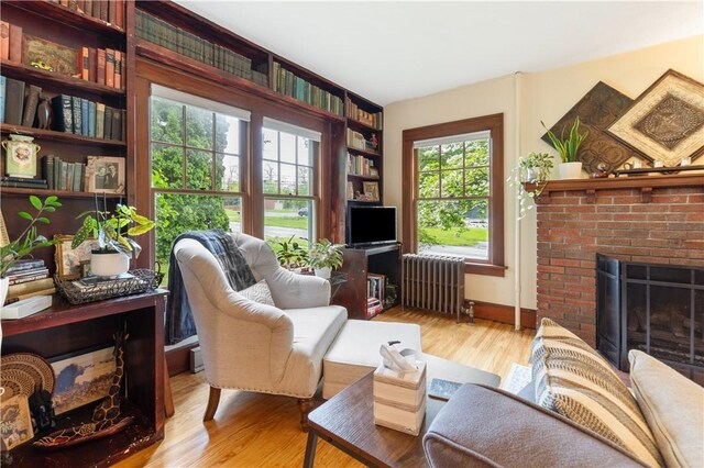 456 N Main St, Benton, NY 14527 - living room featuring radiator heating unit, a brick fireplace, wood finished floors, and baseboards