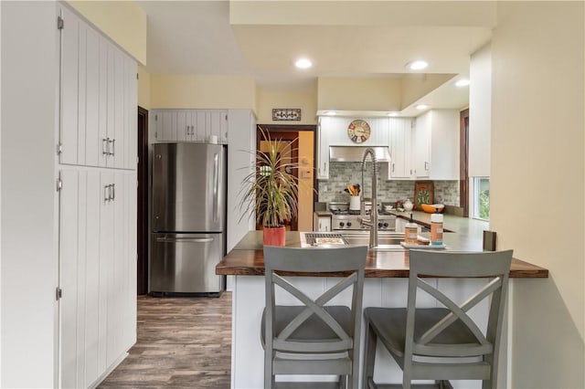 456 N Main St, Benton, NY 14527 - kitchen with freestanding refrigerator, tasteful backsplash, a peninsula, dark wood-style flooring, and dark countertops