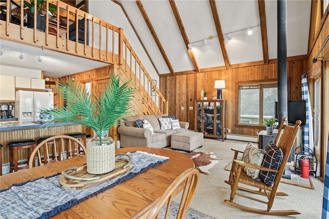 6525 Bonnie Castle Rd, Huron, NY 14590 - dining room with rail lighting, wooden walls, baseboard heating, stairs, and a wood stove