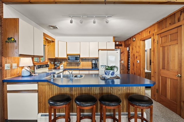 6525 Bonnie Castle Rd, Huron, NY 14590 - kitchen with white appliances, a sink, a peninsula, wood walls, and white cabinetry