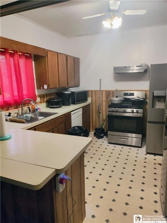 601 Falconer St, Jamestown, NY 14701 - kitchen featuring appliances with stainless steel finishes, extractor fan, a sink, light countertops, and brown cabinetry