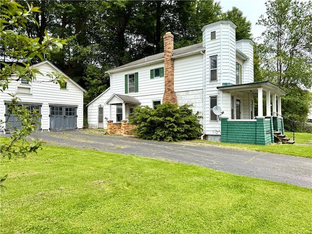 9 Weidman St, Unadilla, NY 13849 - view of front of house featuring a chimney, an outbuilding, a front lawn, covered porch, and a detached garage