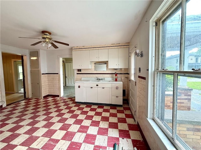 9 Weidman St, Unadilla, NY 13849 - kitchen with light flooring, plenty of natural light, white cabinets, light countertops, and a wainscoted wall
