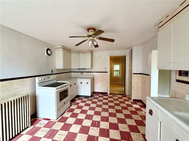 9 Weidman St, Unadilla, NY 13849 - kitchen with radiator heating unit, white range with electric cooktop, a wainscoted wall, light flooring, and tile walls