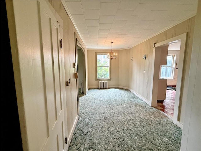 9 Weidman St, Unadilla, NY 13849 - spare room featuring radiator, carpet flooring, a chandelier, crown molding, and wood walls