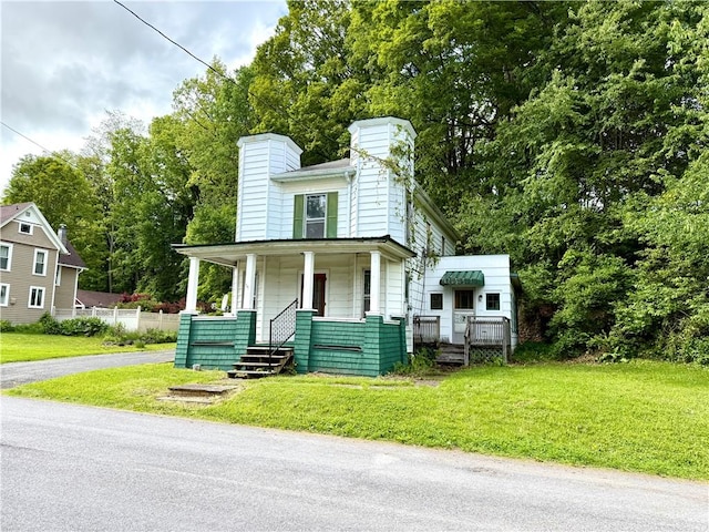 9 Weidman St, Unadilla, NY 13849 - view of front of house featuring a porch, a chimney, a front lawn, and view of scattered trees