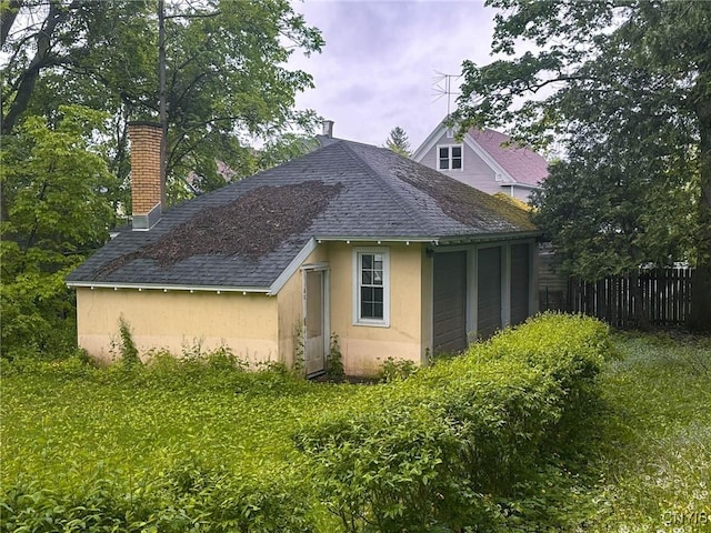 169 Pleasant St, Utica, NY 13501 - view of side of property featuring roof with shingles, stucco siding, and a chimney