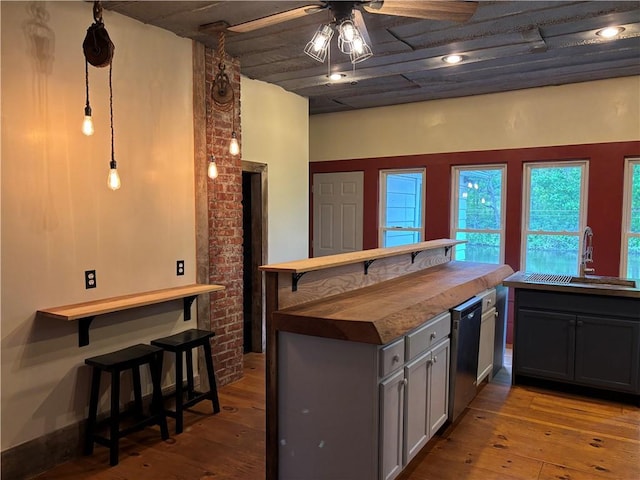 6940 County Highway 18, Plainfield, NY 13491 - kitchen featuring a sink, a ceiling fan, hardwood / wood-style floors, dishwashing machine, and a kitchen breakfast bar
