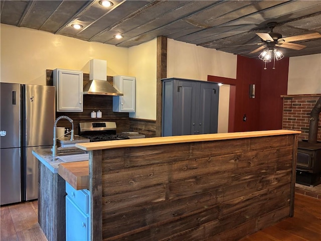 6940 County Highway 18, Plainfield, NY 13491 - kitchen featuring wall chimney exhaust hood, stainless steel appliances, a ceiling fan, and dark wood-style flooring