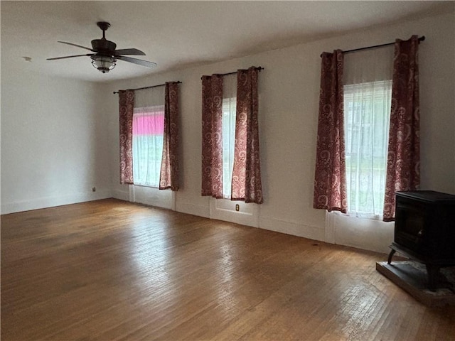 6940 County Highway 18, Plainfield, NY 13491 - empty room with a wood stove, plenty of natural light, wood finished floors, and ceiling fan