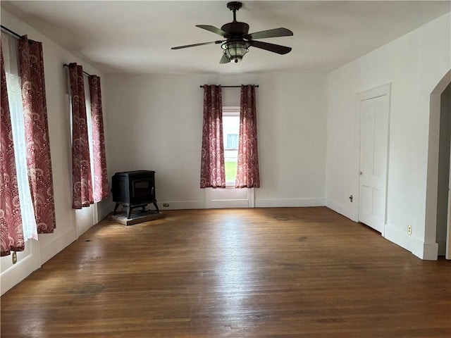 6940 County Highway 18, Plainfield, NY 13491 - unfurnished room featuring a wood stove, a ceiling fan, wood finished floors, arched walkways, and baseboards