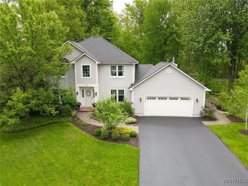 3118 Corlear Dr, Lysander, NY 13027 - view of front of home featuring driveway, an attached garage, a front yard, and a shingled roof