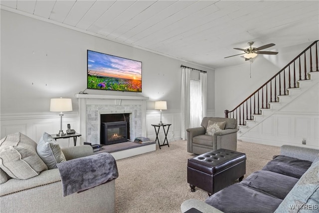 1822 Grover Rd, Aurora, NY 14052 - carpeted living area featuring a decorative wall, ceiling fan, stairs, wainscoting, and a high end fireplace