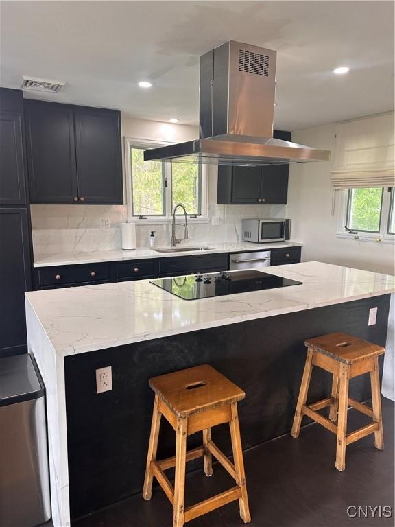 2089 Spring St, Hamilton, NY 13346 - kitchen featuring a sink, island exhaust hood, appliances with stainless steel finishes, a breakfast bar, and decorative backsplash