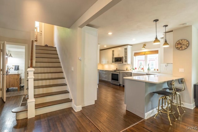 207 Twin Hills Dr, Syracuse, NY 13207 - kitchen featuring appliances with stainless steel finishes, dark wood finished floors, a peninsula, glass insert cabinets, and recessed lighting