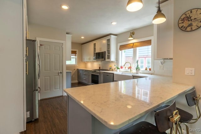 207 Twin Hills Dr, Syracuse, NY 13207 - kitchen featuring stainless steel appliances, a peninsula, decorative backsplash, dark wood finished floors, and glass insert cabinets