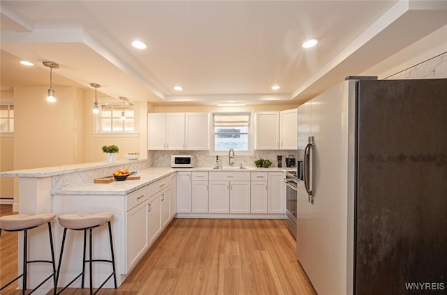 445 Connecticut St, Buffalo, NY 14213 - kitchen with appliances with stainless steel finishes, a sink, a peninsula, light wood-type flooring, and backsplash