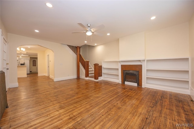 445 Connecticut St, Buffalo, NY 14213 - unfurnished living room featuring ceiling fan, a fireplace, arched walkways, light wood-style flooring, and stairs
