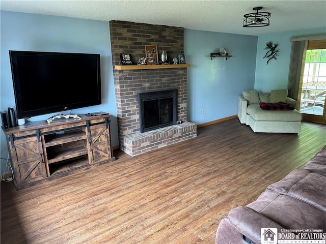 8900 Brownell Rd, Clymer, NY 14724 - living room with wood finished floors, a textured ceiling, a fireplace, and baseboards