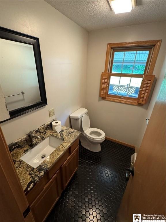 8900 Brownell Rd, Clymer, NY 14724 - bathroom featuring vanity, toilet, a textured ceiling, and tile patterned floors