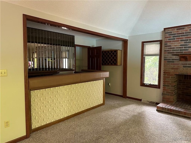 55 Hemlock Ln, Lancaster, NY 14086 - unfurnished living room with carpet flooring, baseboards, vaulted ceiling, a textured ceiling, and a fireplace