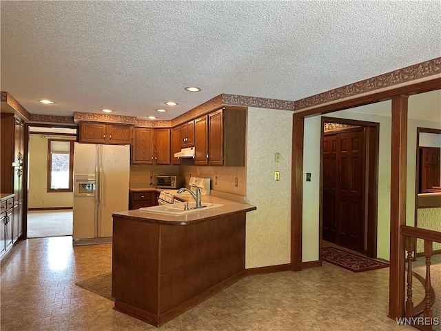 55 Hemlock Ln, Lancaster, NY 14086 - kitchen with white fridge with ice dispenser, a textured ceiling, under cabinet range hood, a sink, and a peninsula