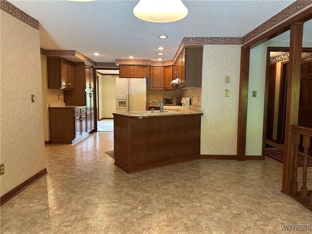 55 Hemlock Ln, Lancaster, NY 14086 - kitchen featuring white refrigerator with ice dispenser, a sink, baseboards, a peninsula, and a textured ceiling