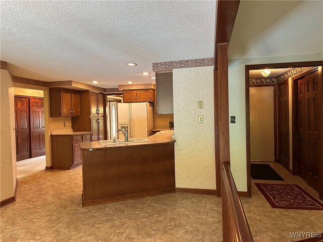 55 Hemlock Ln, Lancaster, NY 14086 - kitchen with white refrigerator with ice dispenser, a sink, a peninsula, a textured ceiling, and light floors